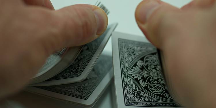 A group of people drawing multiple cards or displaying hands at a card table, focusing on hands and cards