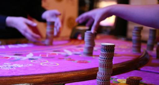 Stock photograph of people flipping a coin, rolling dice, and spinning a colorful wheel at a table, focused on hands and game items, with a bright and inviting atmosphere