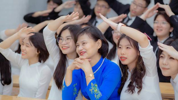A teacher or contest host holding up a randomly drawn number in a classroom or event, with excited participants in the background